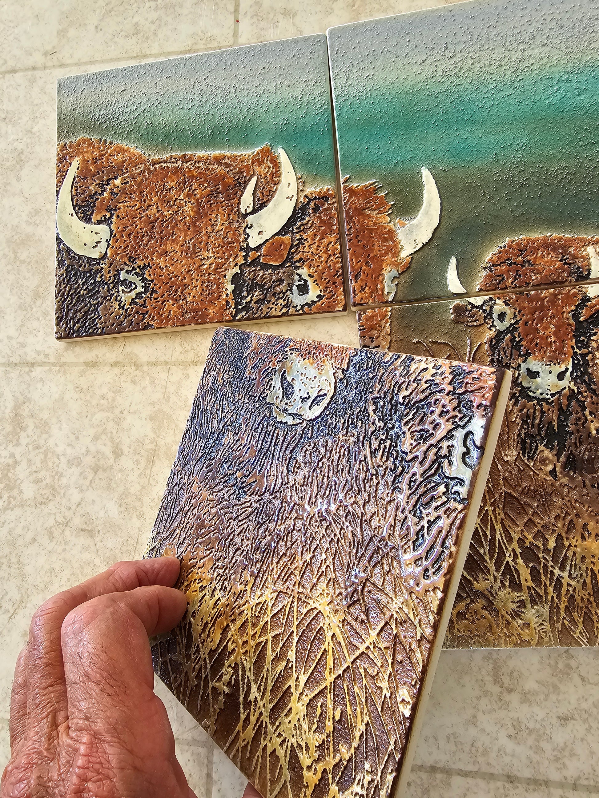 This is a detail view of single tile of a mural of 4 handmade tiles showing 3 American Bison. This view shows the gloss, detail and thickness of a single tile of the mural.
These tiles are handmade porcelain ceramic tiles that could be installed as kitchen wall tiles, kitchen backsplash tiles. 
This image is intended to remind us of our connection to nature.