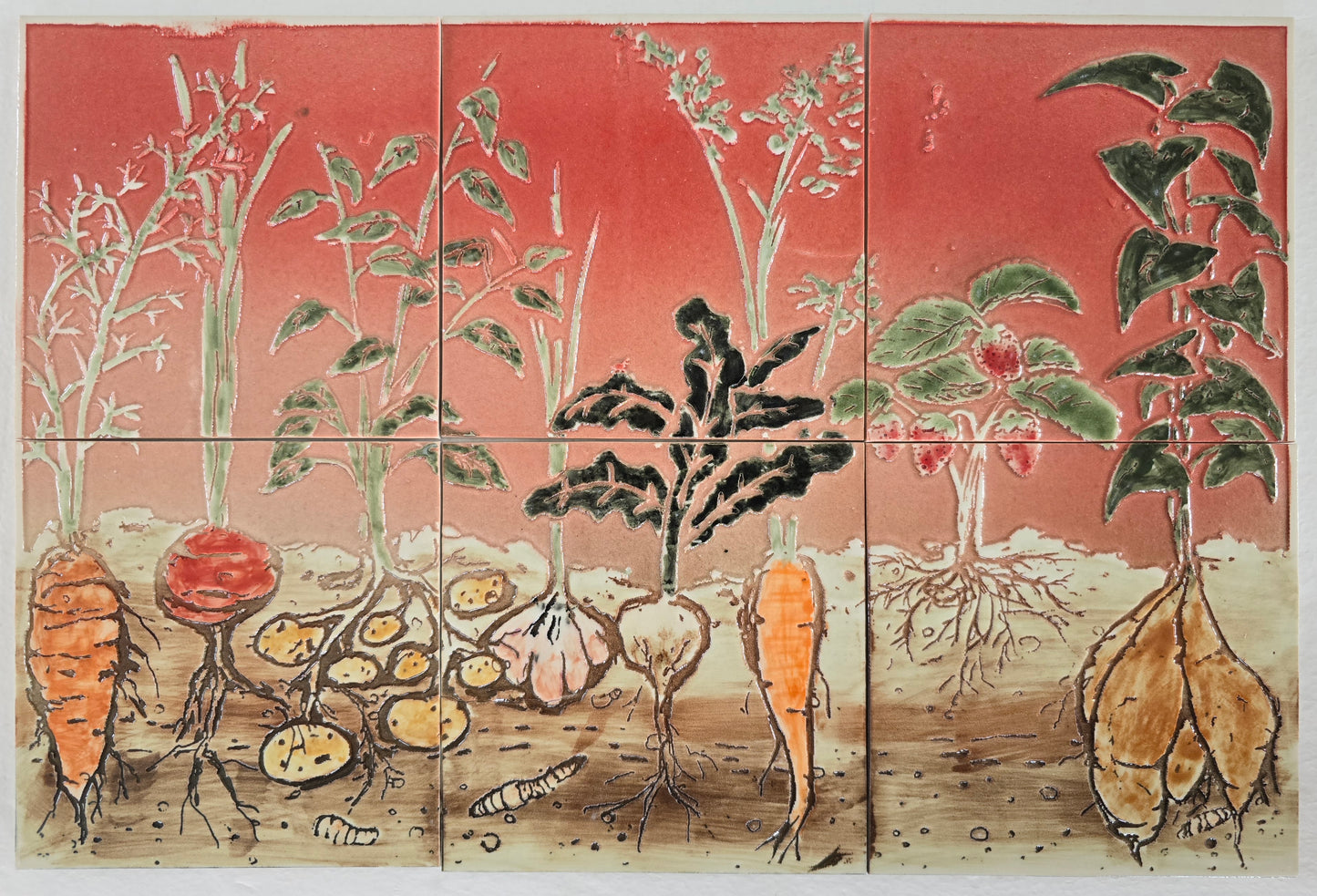 This photo shows the veggies having various shades of green foliage. The real colors are under the surface of the soil. Orange carrots, brown potatoes, red onion, etc. Also the strawberries are red. 
The soil and worms and rocks are brown and roots are darker brown. 
The background field is a red, graduated from darker at the top to lighter at the bottom. 
Since this is a vegetable-oriented subject, it would be good to place it as a kitchen backsplash or kitchen wall tile decoration.